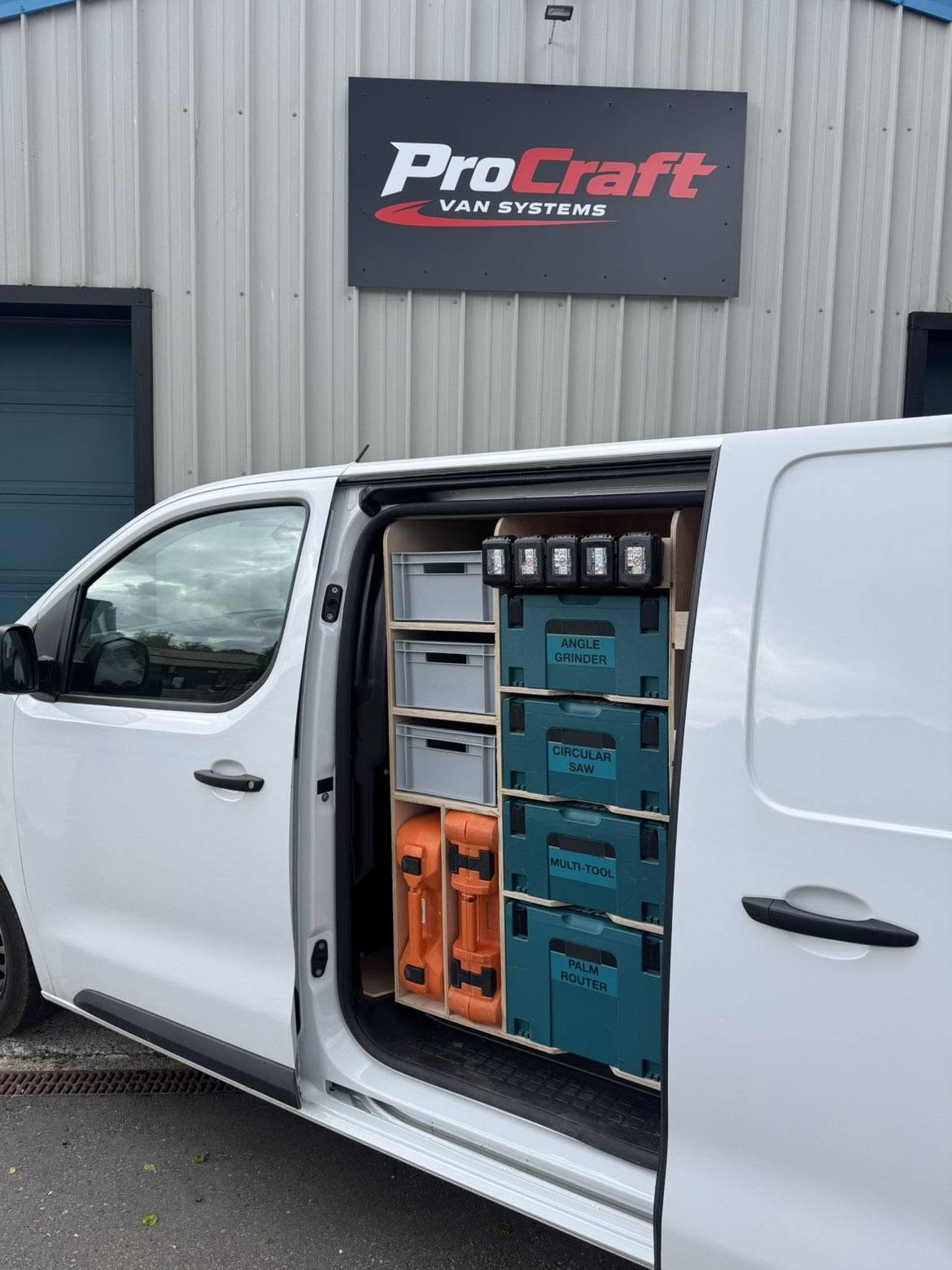 Bespoke plywood van racking with labelled power tool storage boxes fitted in a commercial van
